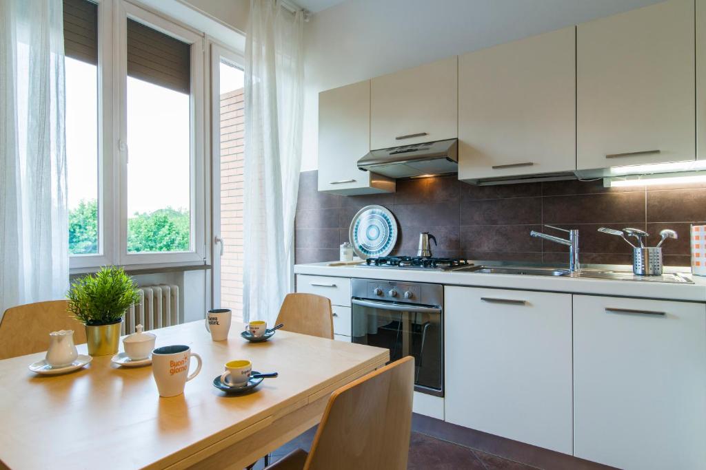 une cuisine avec des placards blancs et une table en bois dans l'établissement Porta Al Prato Cozy Apartment, à Florence