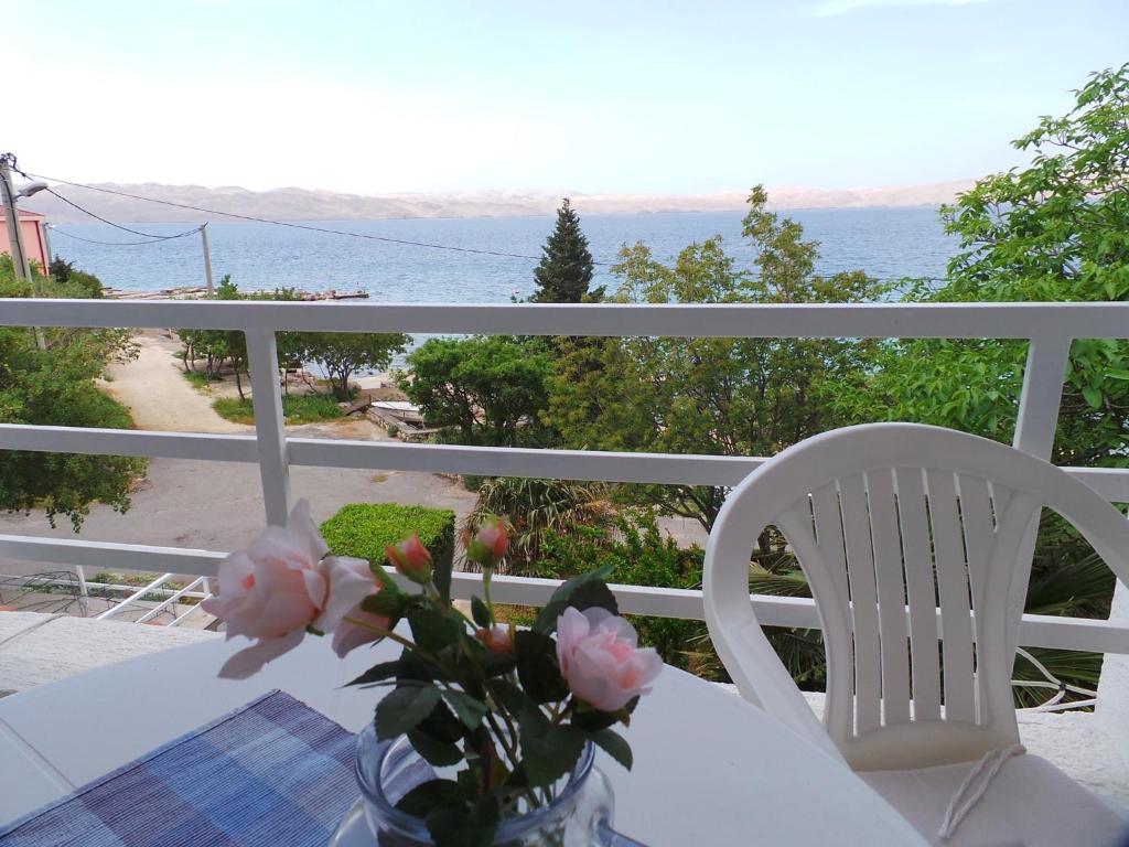 una mesa con un jarrón de flores en el balcón en Apartmani Vjera en Ribarica