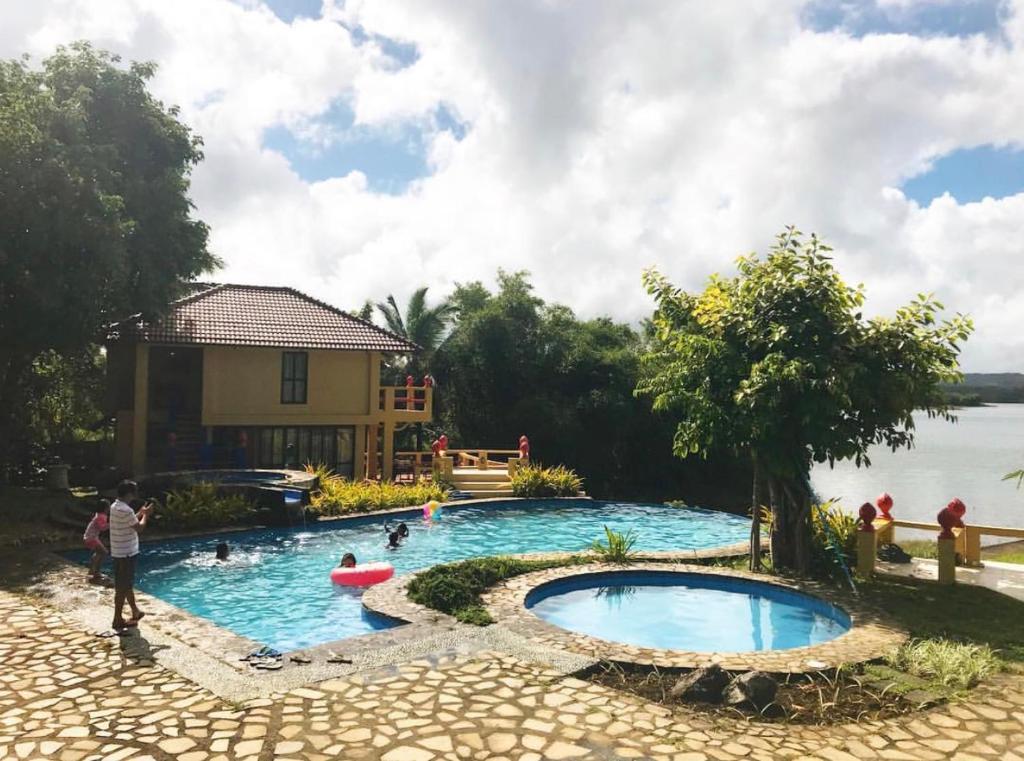 a pool at a resort with people swimming in it at Porta Verde Resort Villas Caliraya in Cavinti