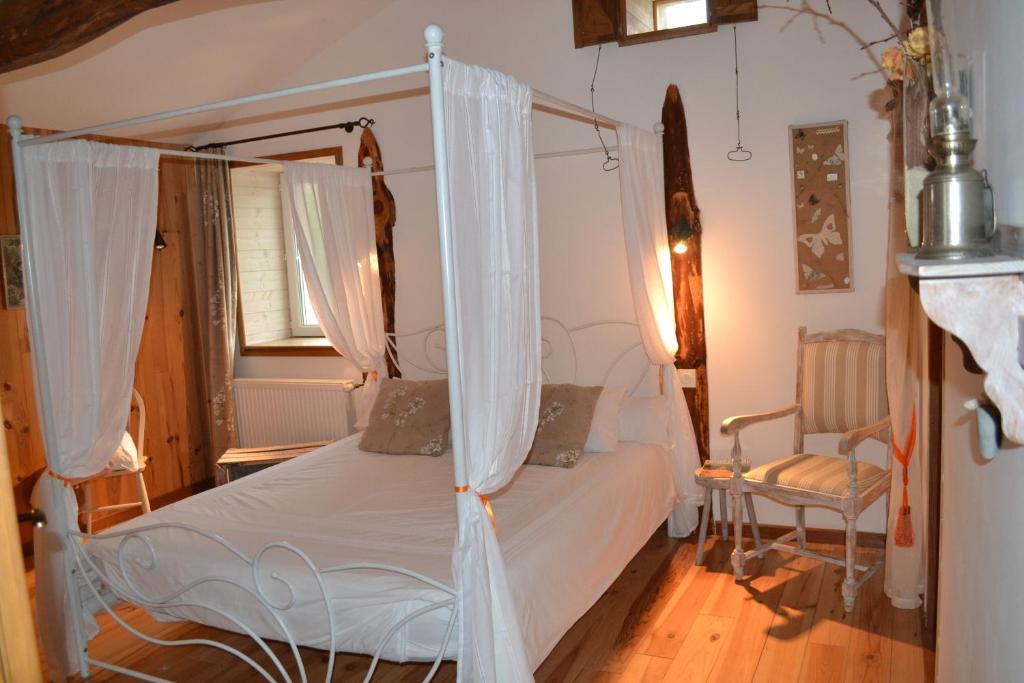 a bedroom with a canopy bed and a chair at Le Jardin des Pierres Brunes in Saint-Jean-des-Ollières