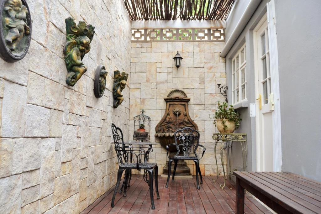 a room with two chairs and a stone wall at Versailles Self-Catering in Wellington