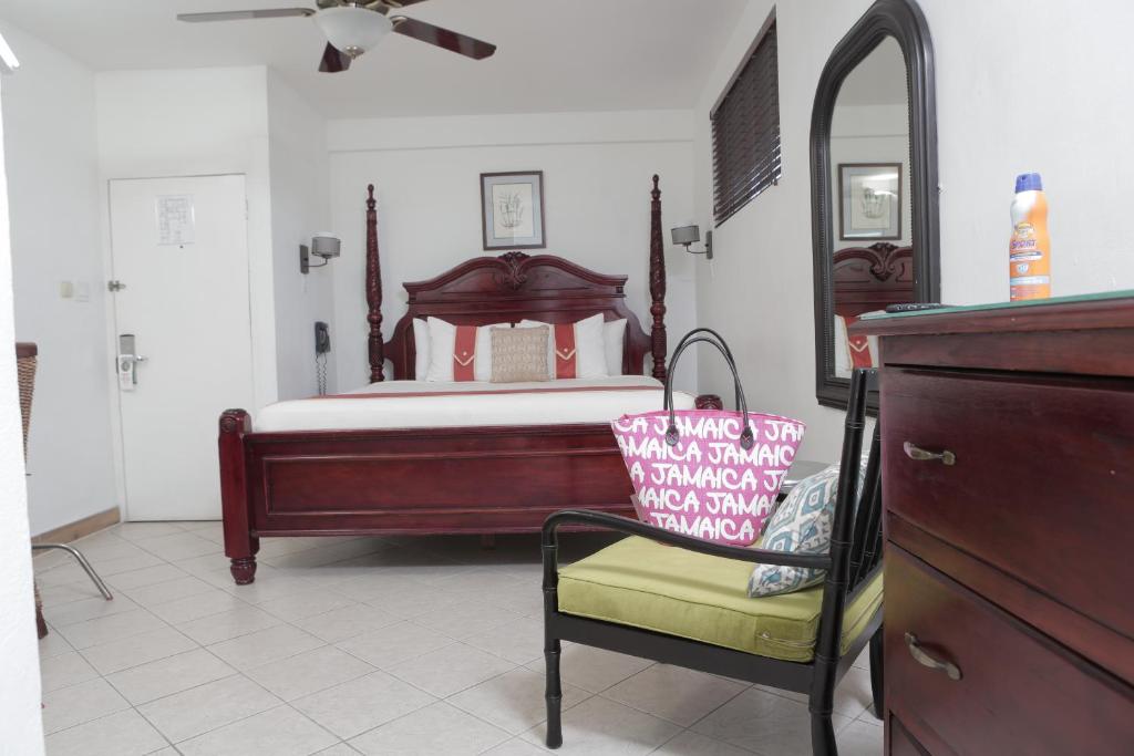 a bedroom with a bed and a chair and a dresser at Altamont West Hotel in Montego Bay