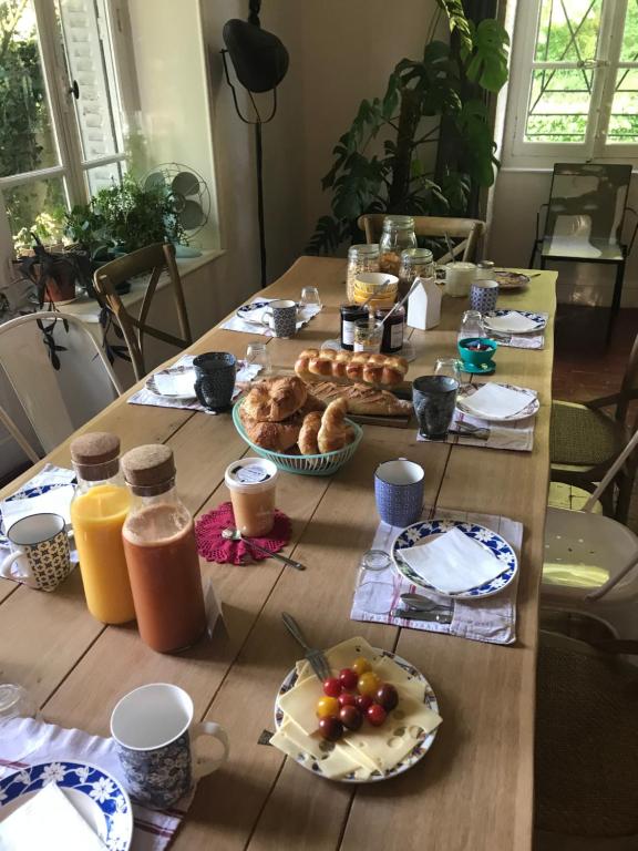 une table en bois recouverte de assiettes de nourriture et de jus d'orange dans l'établissement Les Chambres d'Hôtes du Bois Joli, à Semur-en-Auxois