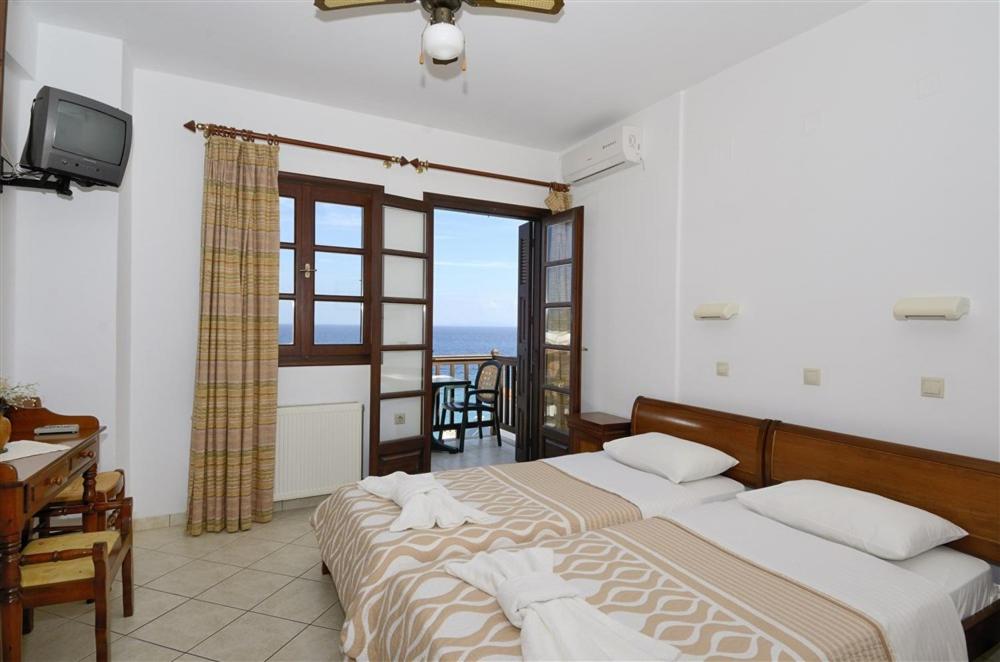 a bedroom with two beds and a view of the ocean at Achinos Apartments and Maisonettes in Kokkari