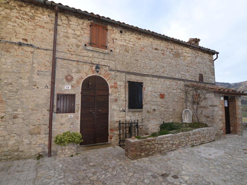 an old stone building with a brown door and a building at Belvilla by OYO Graceful Apartment with Garden in Petrella Guidi