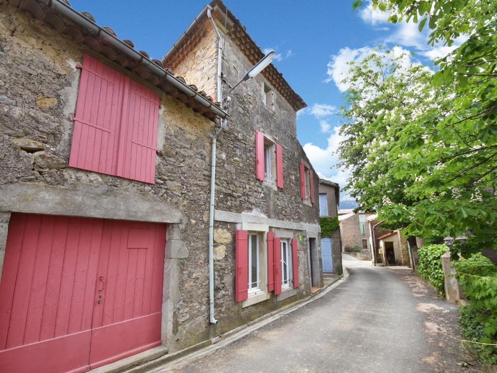 a street with red garage doors on a stone building at Village House in La Caunette with Pool in La Caunette