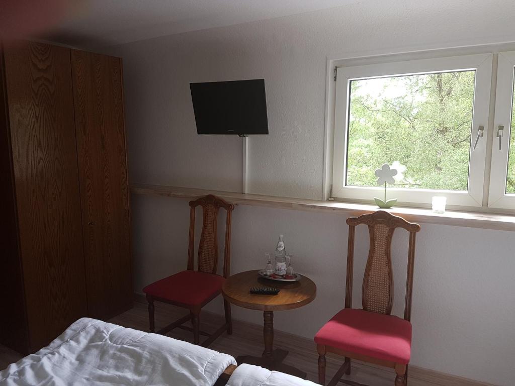 a bedroom with two chairs and a table and a window at Forellenhof-Waldhölzbach in Waldhölzbach