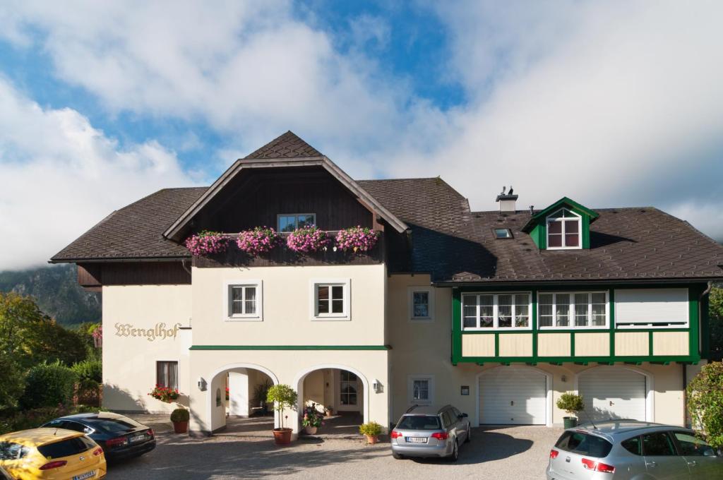 una casa grande con coches aparcados en un aparcamiento en Hotel Garni Wenglhof en Sankt Gilgen