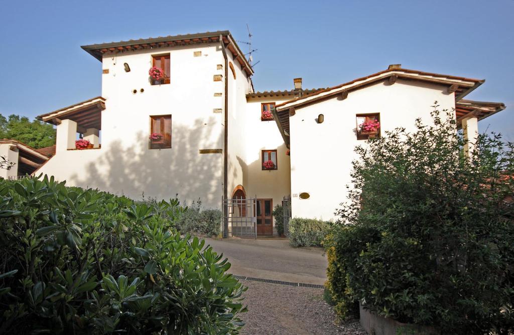 a white house with red flowers in the windows at Tenuta Il Burchio in Incisa in Valdarno