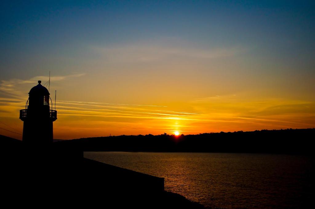 a lighthouse with the sunset in the background at Youghal in Youghal