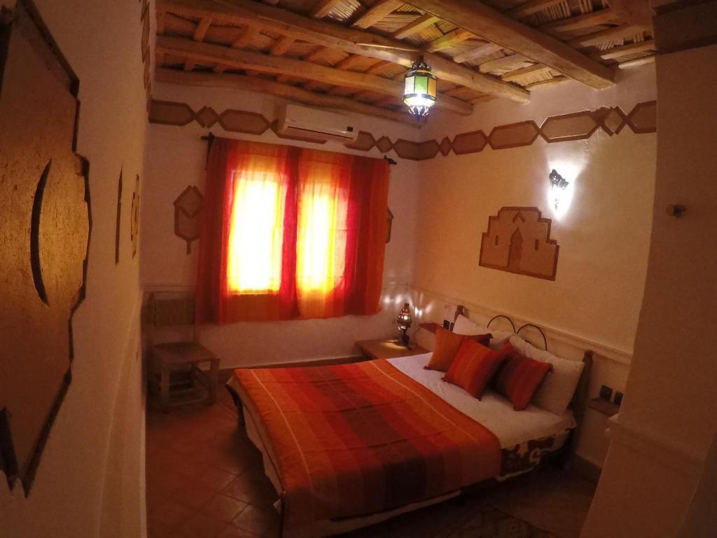 a bedroom with a bed with red pillows and a window at Auberge des peupliers Café Restaurant in Akhendachou nʼAït Ouffi