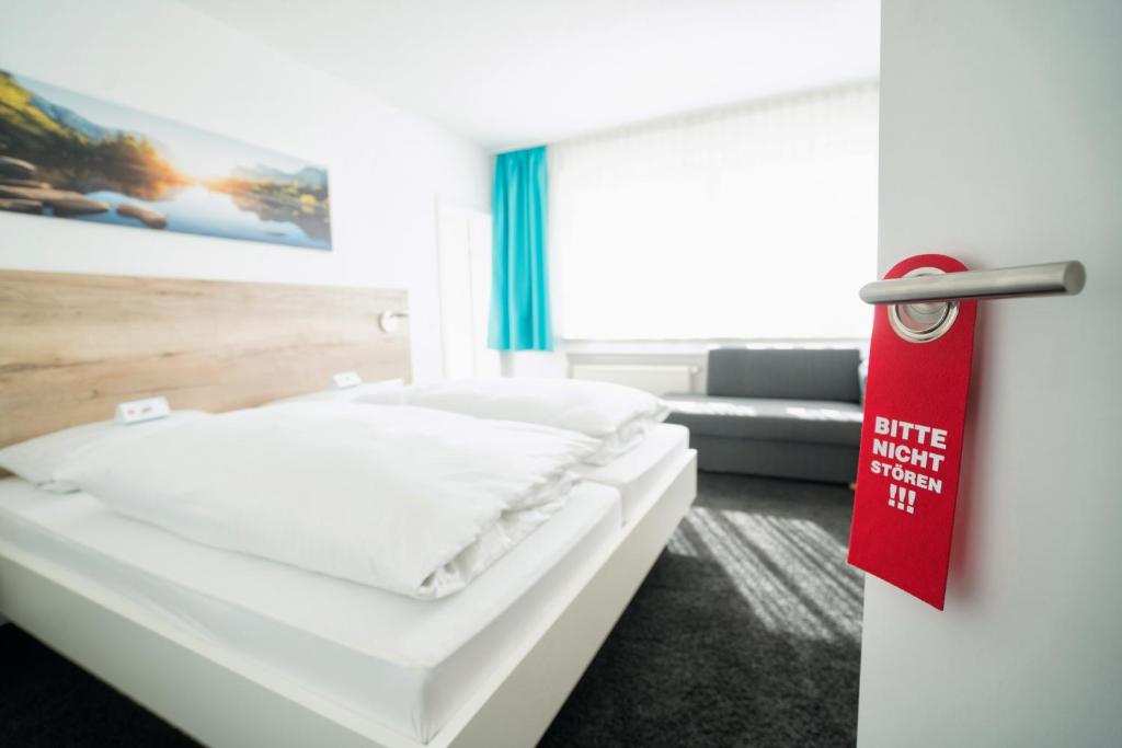 a room with a bed with a red sign on the door at Hotel zur Sonne in Bodelshausen