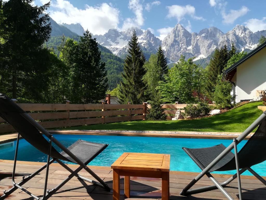 un par de sillas y una mesa junto a una piscina en Hiša Katja-Privat wellness, en Kranjska Gora