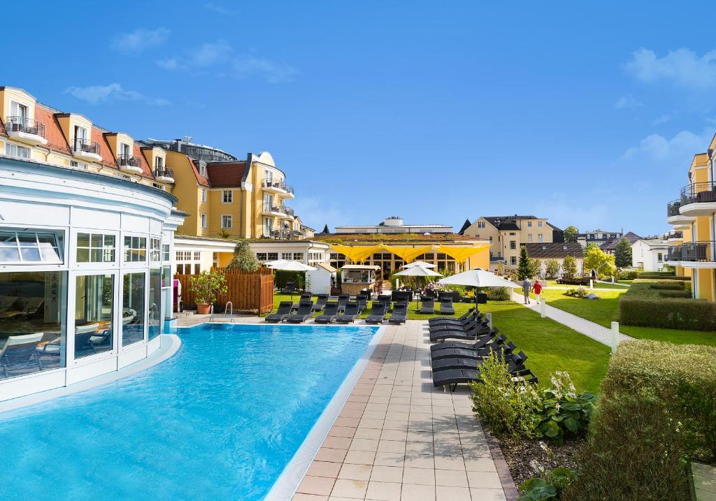 a swimming pool with chairs and a building at Hotel zur Post - ein Rovell Hotel in Bansin