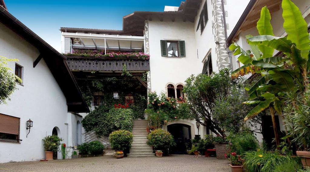 Biały dom z kwiatami i roślinami w obiekcie Ansitz Wendelstein w mieście Appiano sulla Strada del Vino