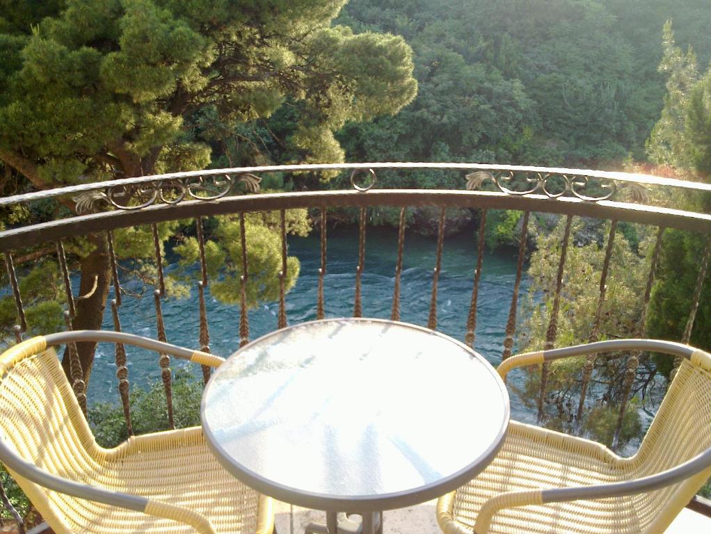 d'une table et de chaises sur un balcon avec vue sur l'eau. dans l'établissement Villa Park, à Mostar