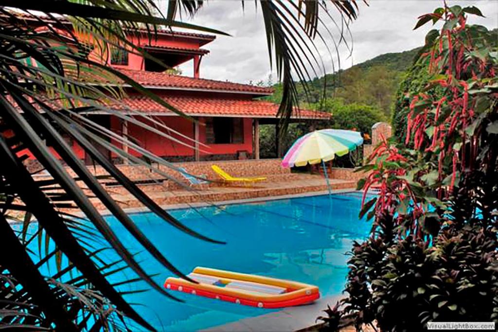 uma piscina com duas jangadas e um guarda-chuva em Pousada Casa de Pedra em Iporanga