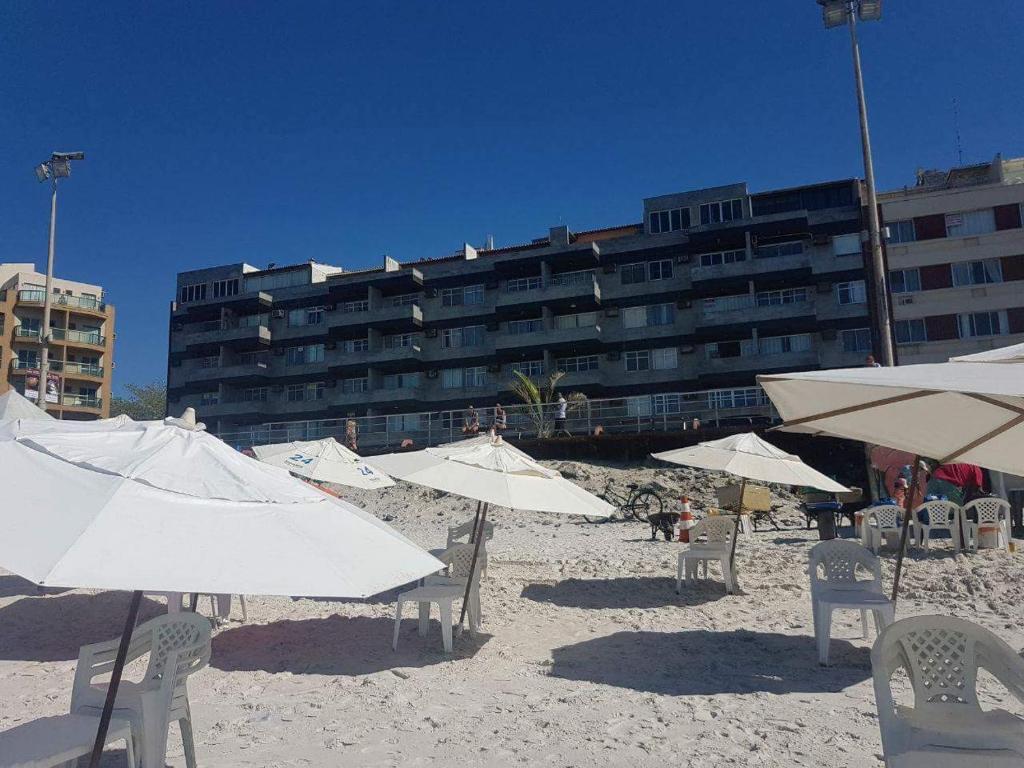 una playa con sillas y sombrillas frente a un edificio en Maravilhoso apartamento de 2 quartos com vista mar en Cabo Frío