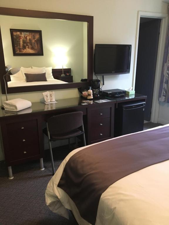 a hotel room with a desk with a bed and a television at Auberge Centre Ville in Saguenay