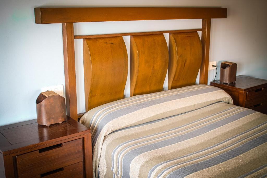 um quarto com uma cama com uma cabeceira em madeira e uma mesa de cabeceira em Hotel Rural Casa La Era em Galve