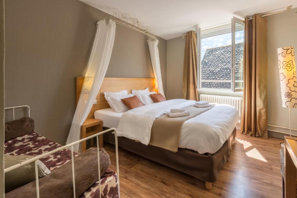 a bedroom with a canopy bed and a window at Contact Hôtel Le Relais de Vellinus in Beaulieu-sur-Dordogne