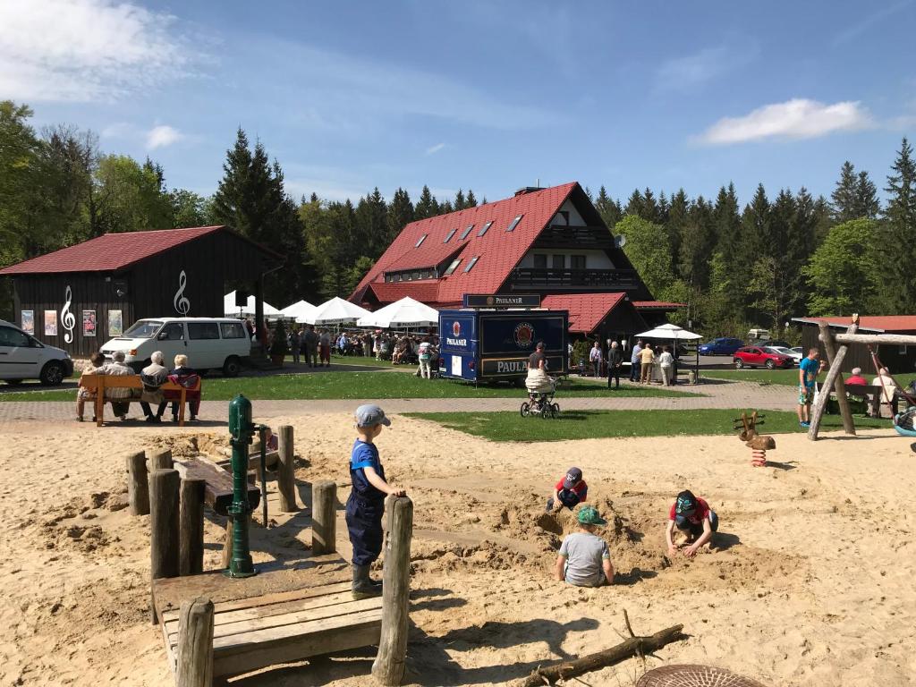 a group of children playing in the sand in front of a building at Berggasthof Heuberghaus in Friedrichroda