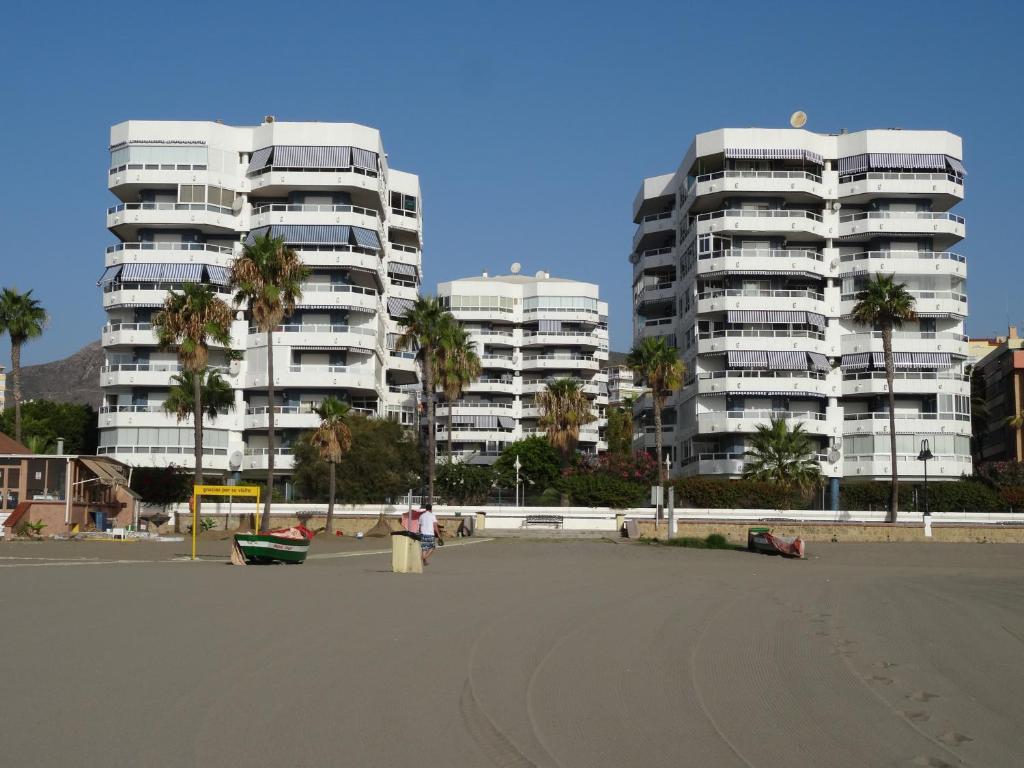 zwei hohe Gebäude auf einem Parkplatz mit Palmen in der Unterkunft Residencia Pez Espada in Torremolinos