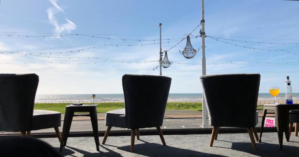 a group of chairs in front of a window with the beach at Seafront419 By Seafront Collection in Blackpool