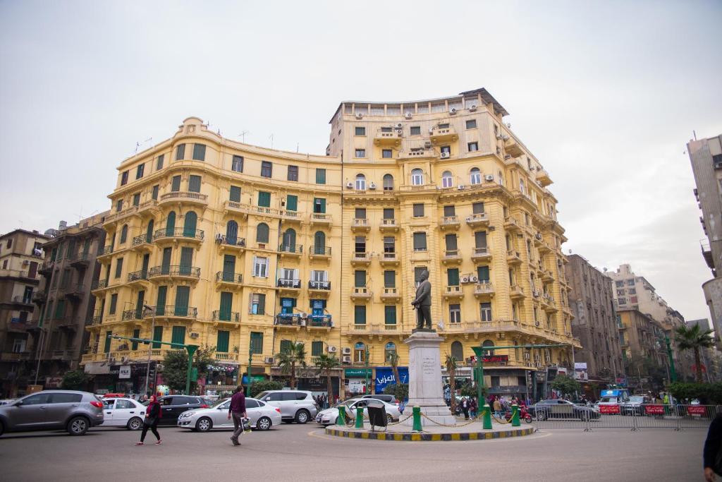 un grand bâtiment jaune avec une statue devant lui dans l'établissement New Grand Royal Hotel Cairo, au Caire