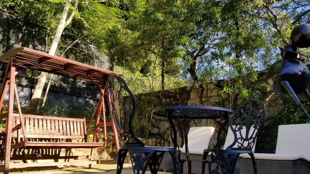 a table and chairs next to a wooden swing at Altamont West Hotel in Montego Bay