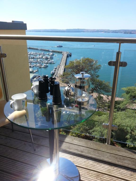 a glass table on a balcony with a view of a harbor at Panoramic sea views, sleeps 4, Torquay in Torquay