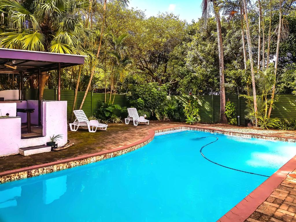 a swimming pool with chairs and a house at Villa Tropicana - South Africa in Margate
