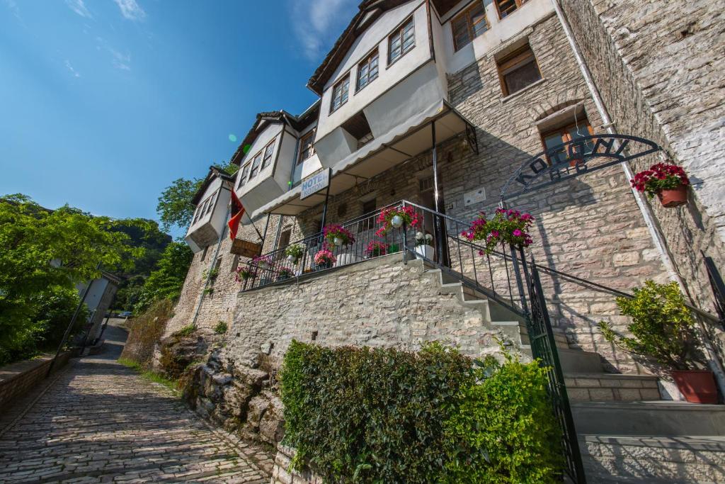 a stone building with flowers on the balconies and stairs at Bed and Breakfast Kotoni in Gjirokastër