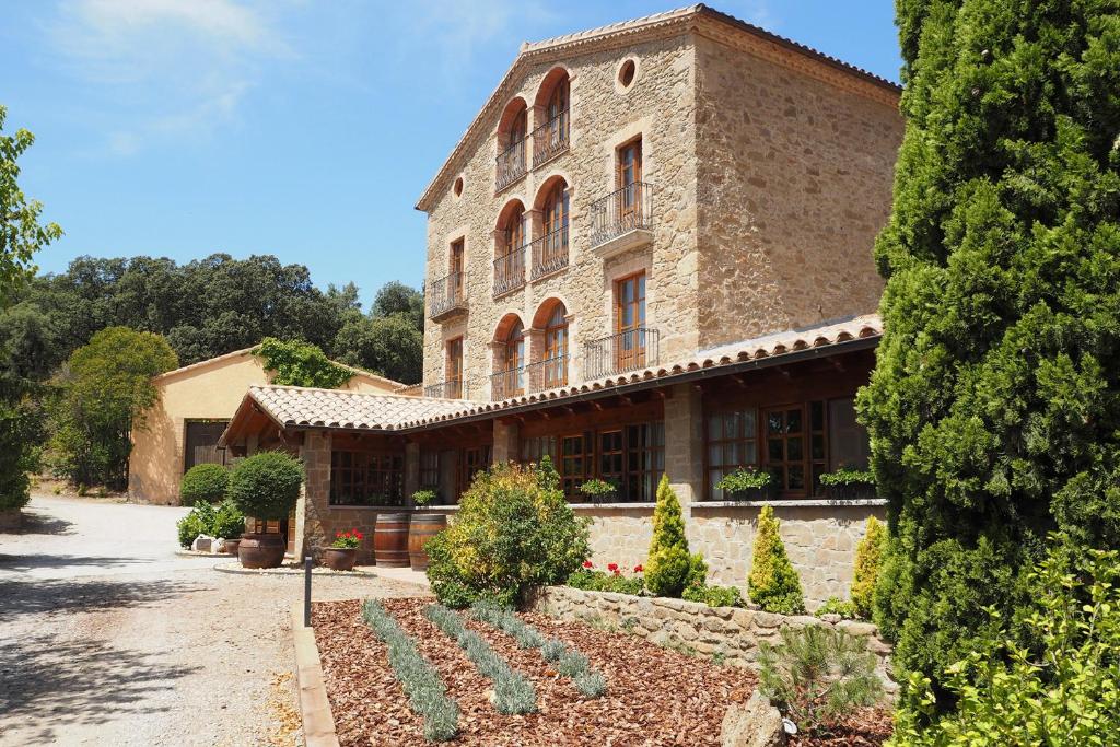 um grande edifício de tijolos com um jardim em frente em Cal Majoral em L'Espunyola