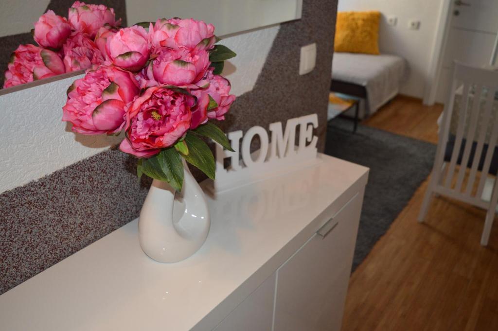 een witte vaas met roze bloemen op een toonbank bij Apartments Iva in Makarska