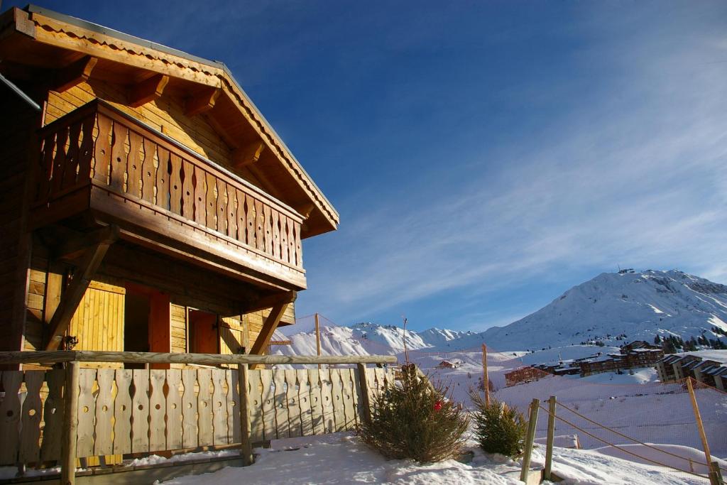 Una cabaña de troncos en la nieve con una montaña en Madame Vacances les Chalets des Alpages, en La Plagne