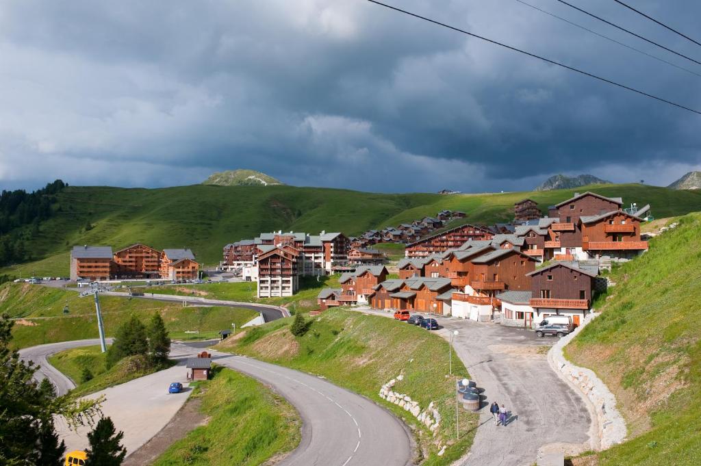 un village sur une colline avec une route sinueuse dans l'établissement Madame Vacances les Chalets des Alpages, à La Plagne