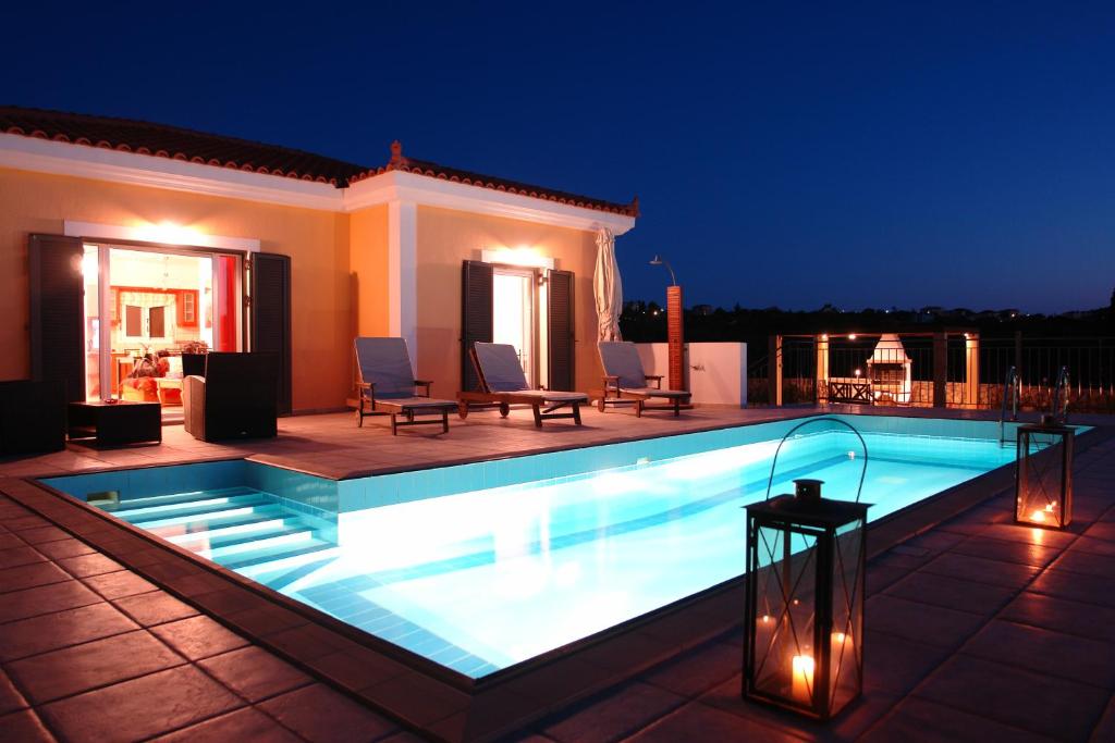 a swimming pool with lights on a patio at night at Europesvilla Io in Lakíthra