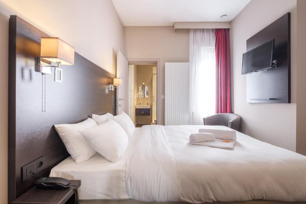 een hotelkamer met een wit bed met een boek erop bij Best Budget Rooms in Brussel