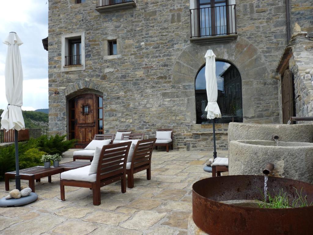 een patio met stoelen en een fontein voor een gebouw bij Hotel Posada Al Vent - Adults Only in Coscojuela de Sobrarbe