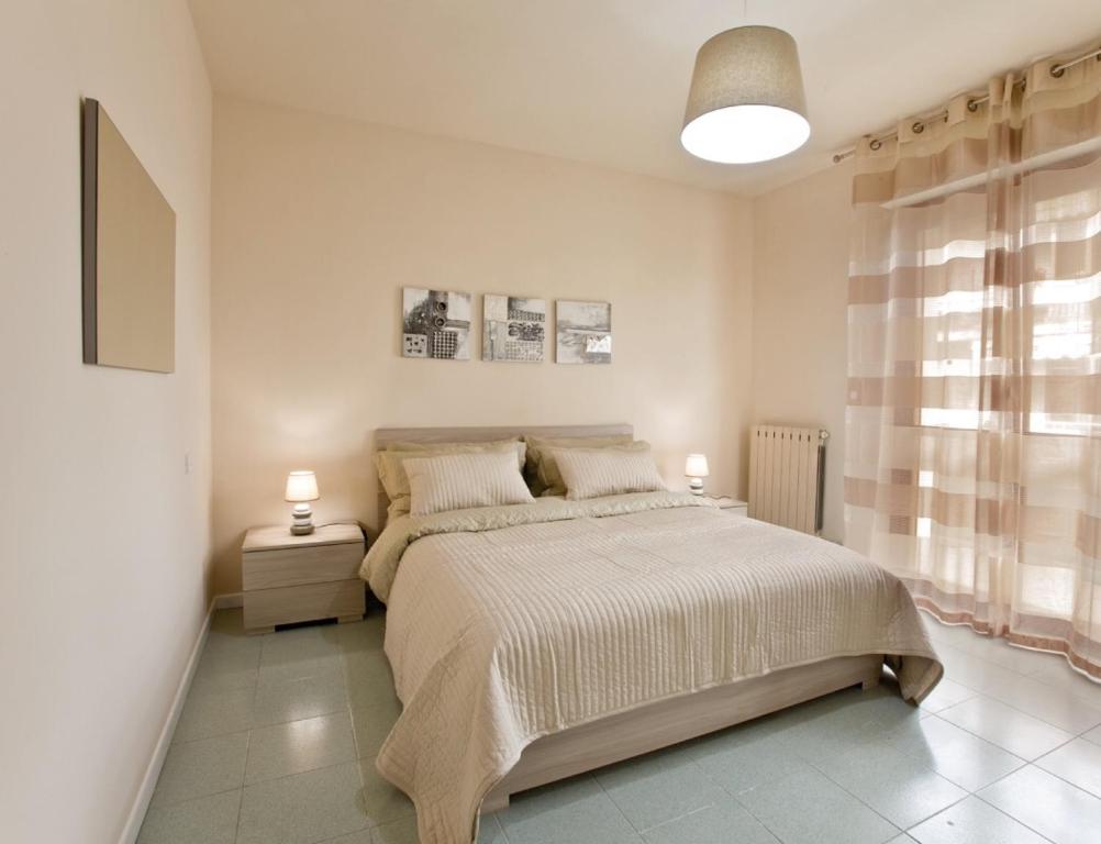 a white bedroom with a large bed and two lamps at Residence "Canta" in Pescara