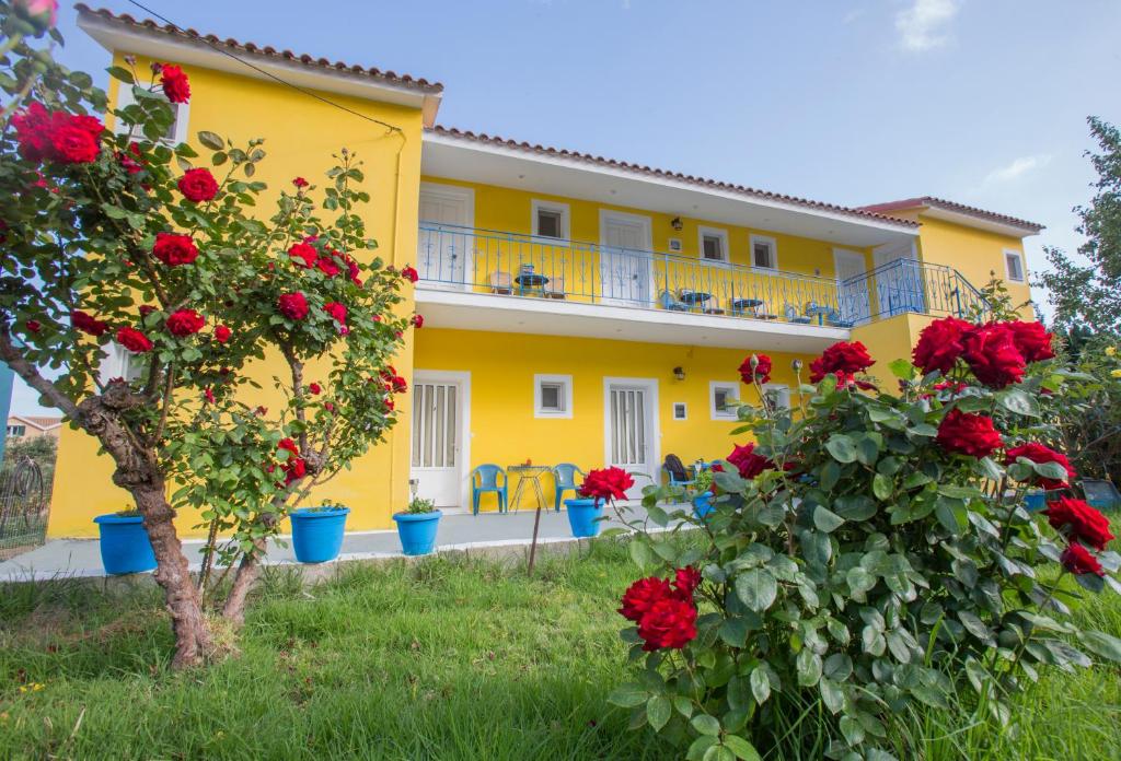 a yellow building with red roses in front of it at Anastasia Studios Katelios in Katelios