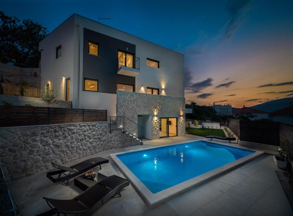 a villa with a swimming pool in front of a building at Villa Salt - 10 people, heated pool, Trogir, near beach & Split airport in Trogir