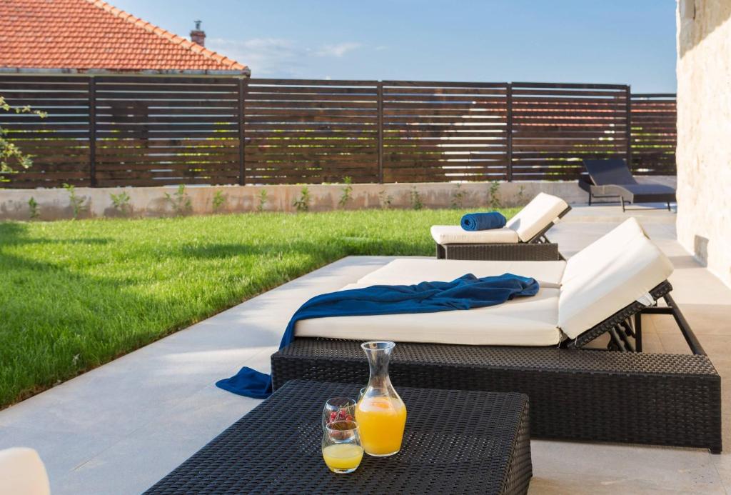 a patio with two beds and two glasses of orange juice at Villa Salt - 10 people, heated pool, Trogir, near beach & Split airport in Trogir