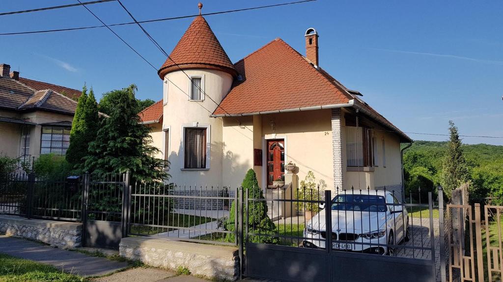 ein weißes Haus mit einem braunen Dach und einem Zaun in der Unterkunft Villa Maria Apartman in Miskolctapolca