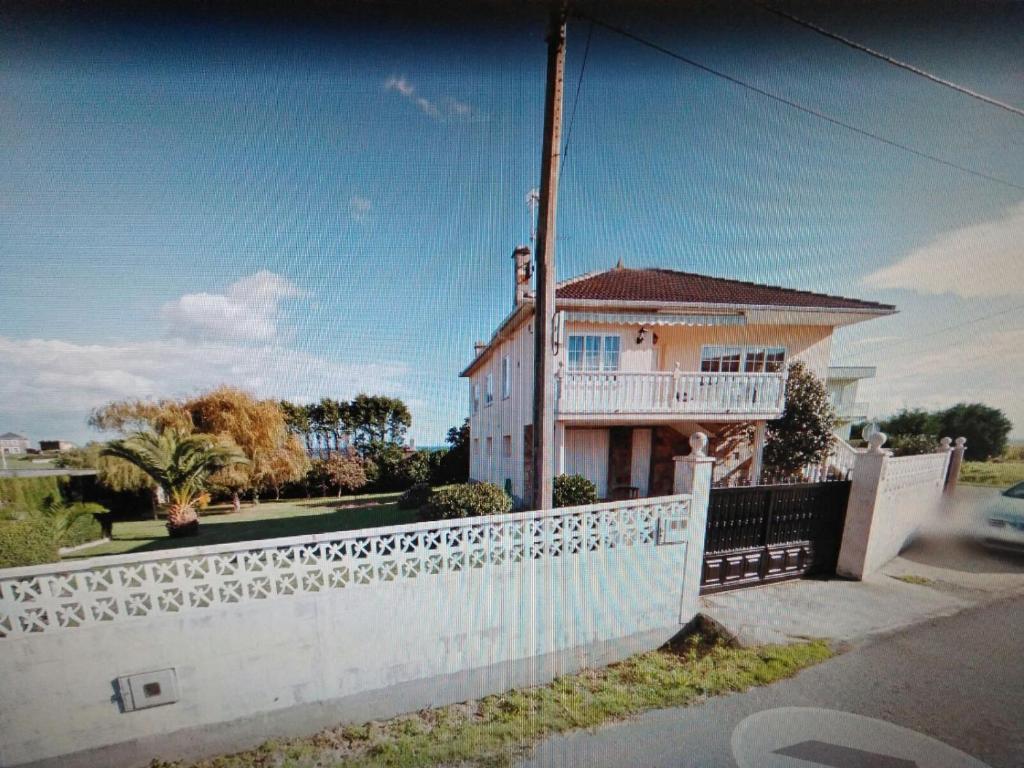 una cerca blanca frente a una casa en Chalet vacacional en segunda linea de playa, en Foz