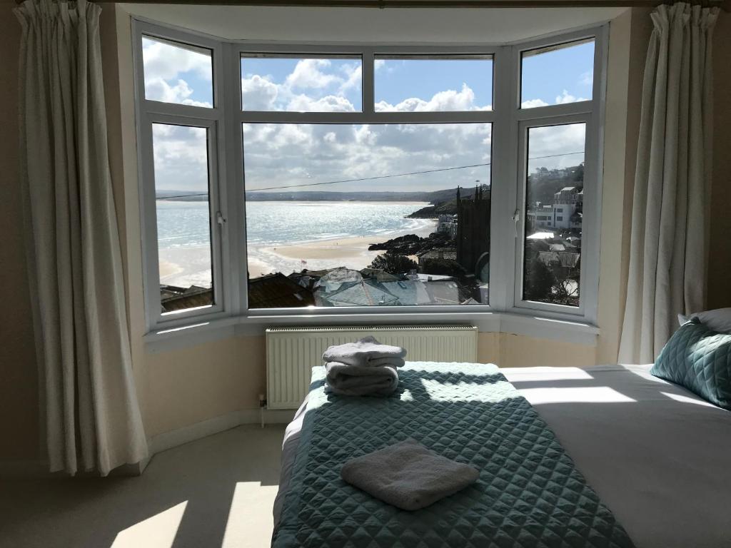 a bedroom with a large window with a view of the ocean at Palma Guest House in St Ives