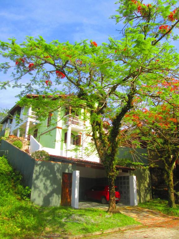a white house with a tree in front of it at Homestay Villa Giulia in Juquei