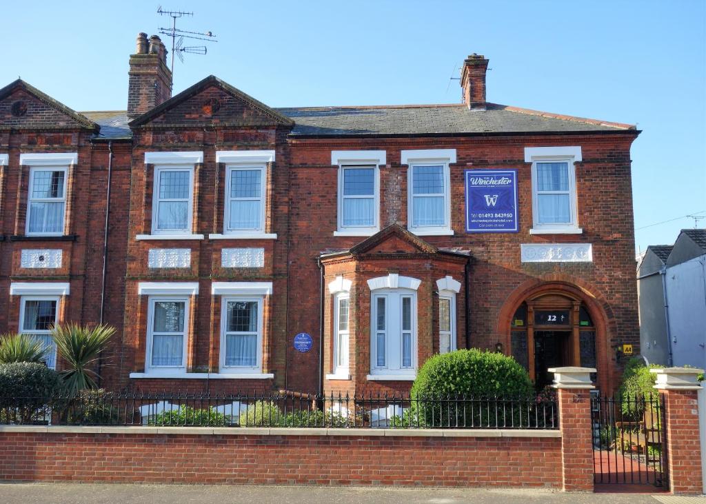 a red brick house with a blue sign on it at The Winchester in Great Yarmouth