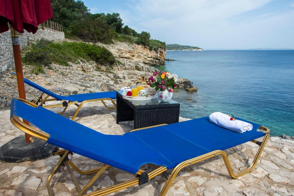 two blue chairs sitting on the beach near the water at Paxos Sunrise Villas in Gaios